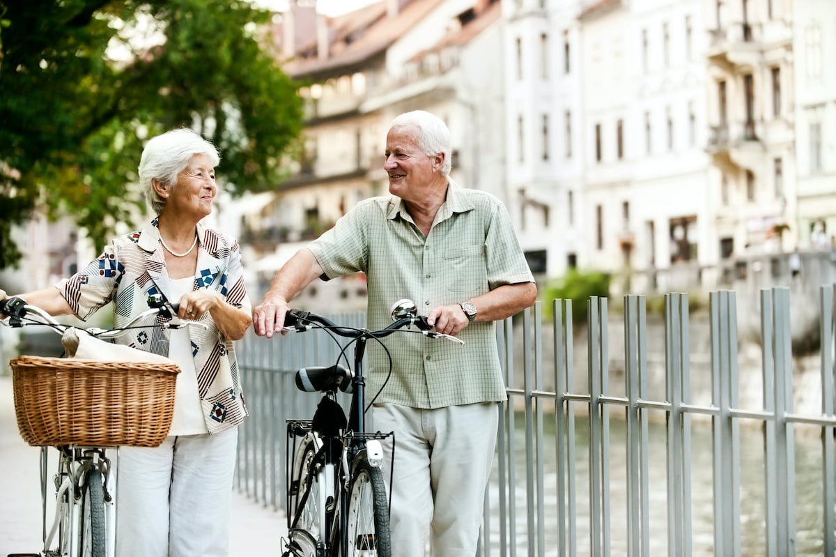 Man en vrouw die met hun fietsen naast een rivier lopen