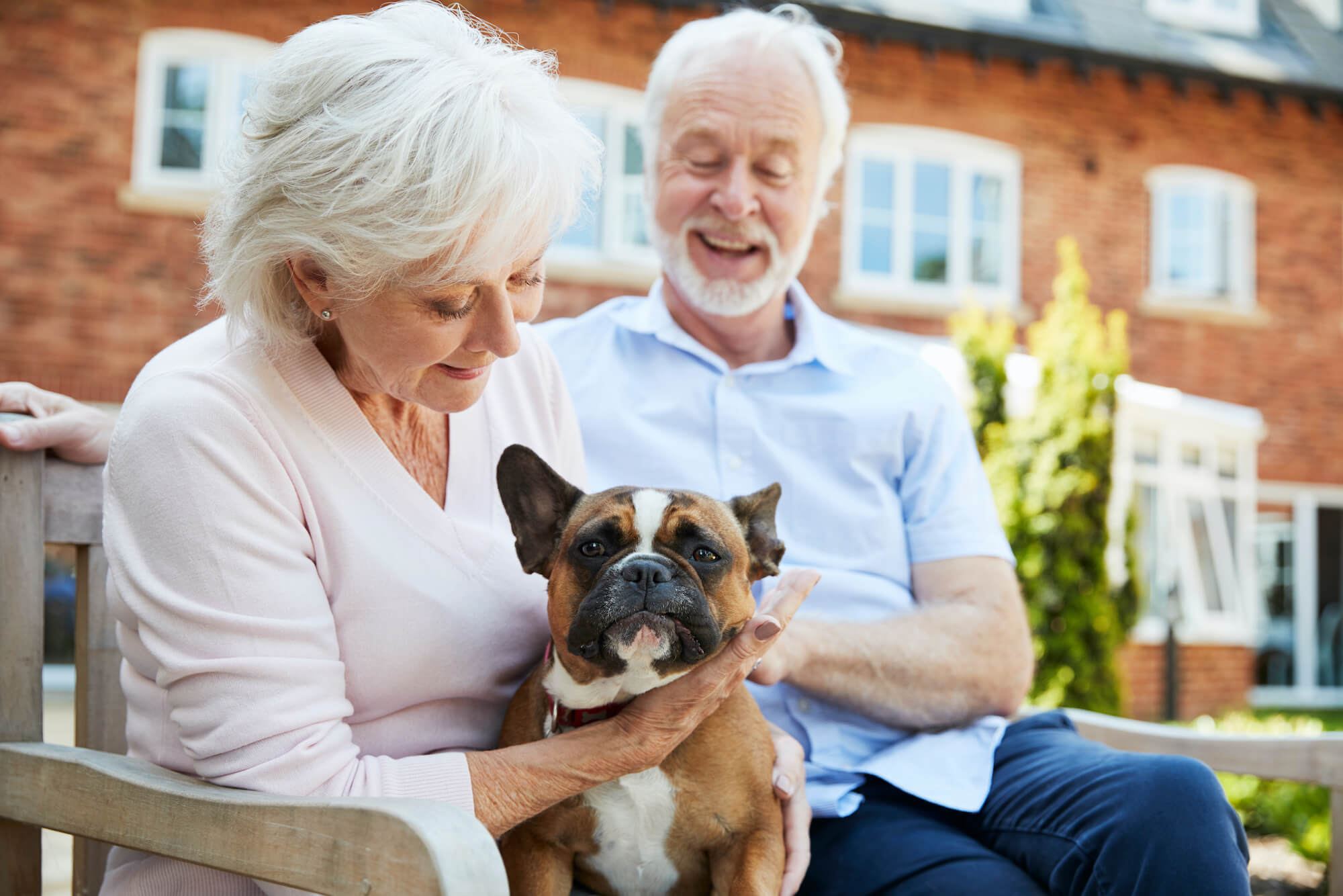 Man en vrouw die hun hond vasthouden terwijl ze op een bankje zitten